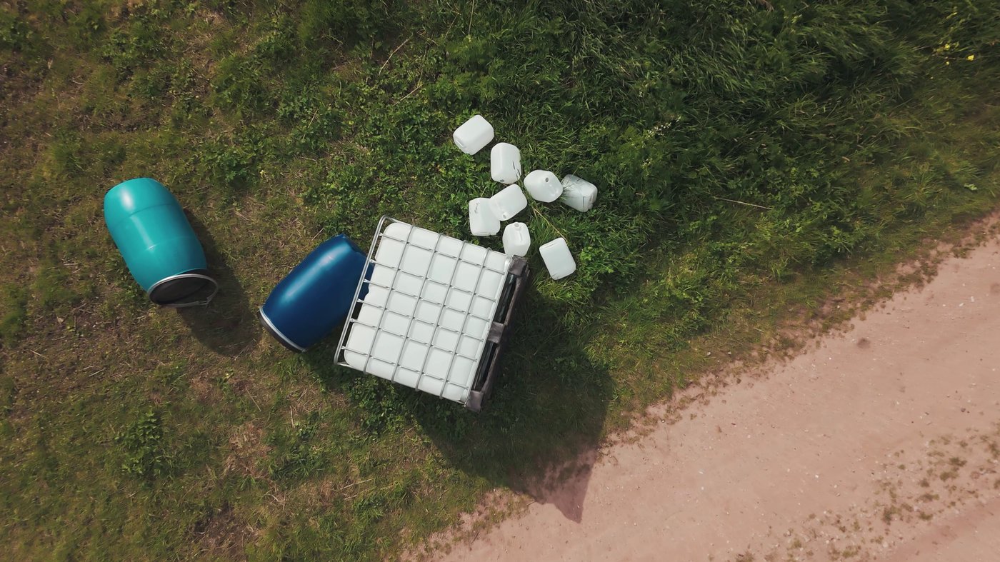 Nagebootste drugsdumping met vaten, jerrycans en een IBC-container in het buitengebied
